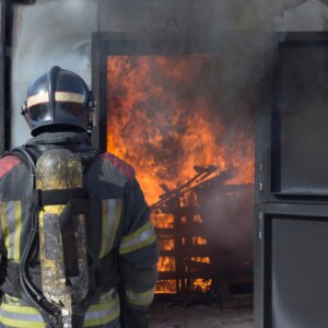 Firefighter facing flames behind door frame