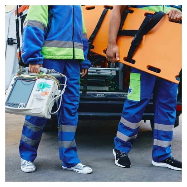 EMS professionals carrying equipment and stretcher outside ambulance