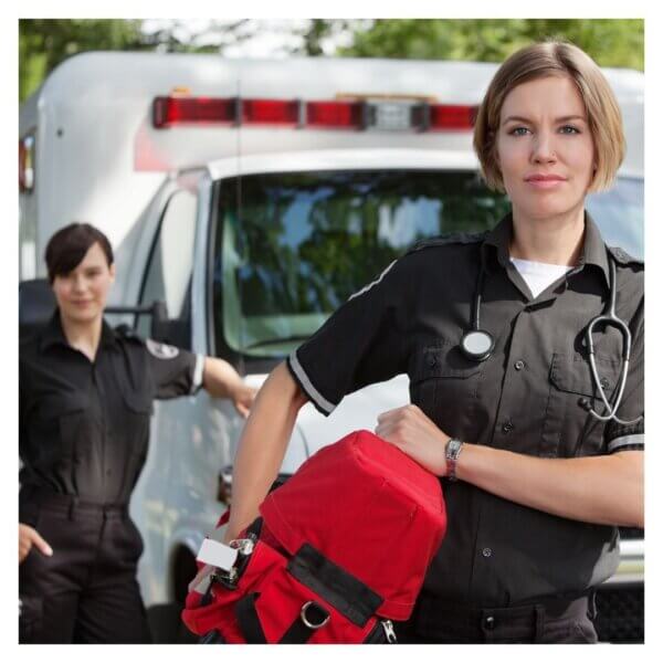 Two female paramedics standing confidently by ambulance