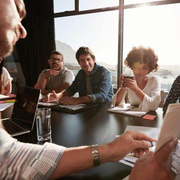 people sit at meeting table looking at presenter