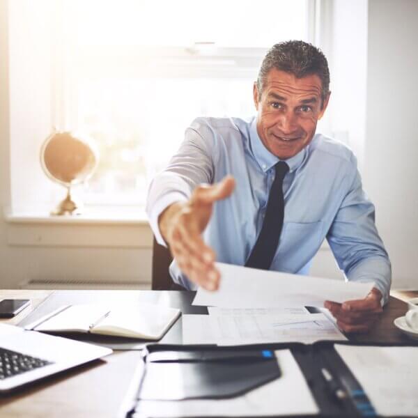 man in business attire reaches out to shake hands 