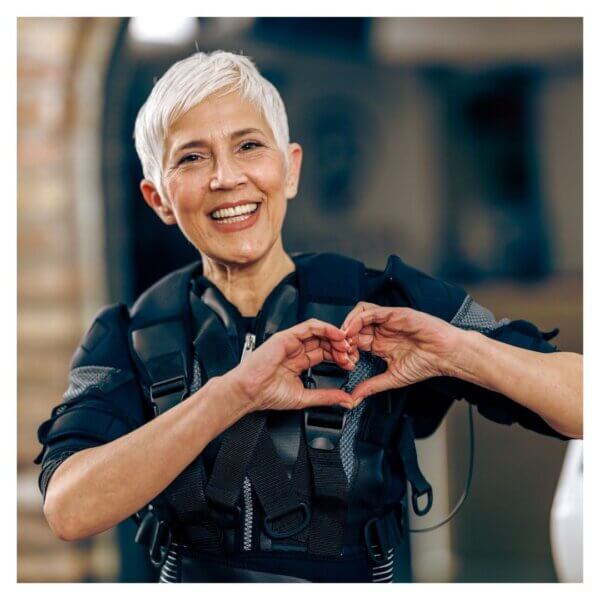 Older woman making heart shape with hands, smiling