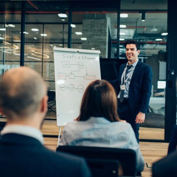 man stands next to white board at meeting