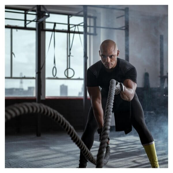 Man performing battle ropes exercise in a gym