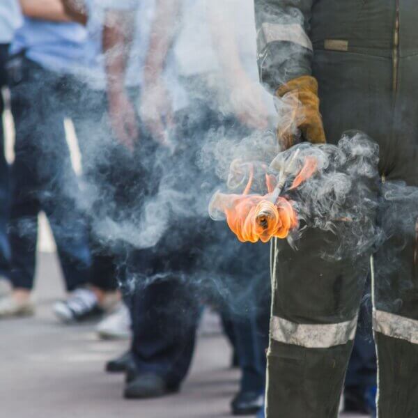 person in fire suit holds a flaming torch