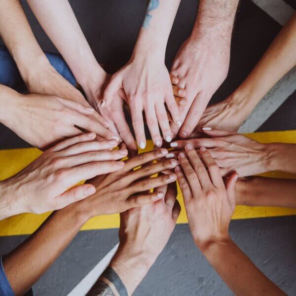 Hands of diverse individuals united in a teamwork gesture
