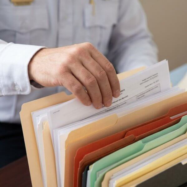 A firefighter's hand is shown methodically organizing administrative paper memos into folders.